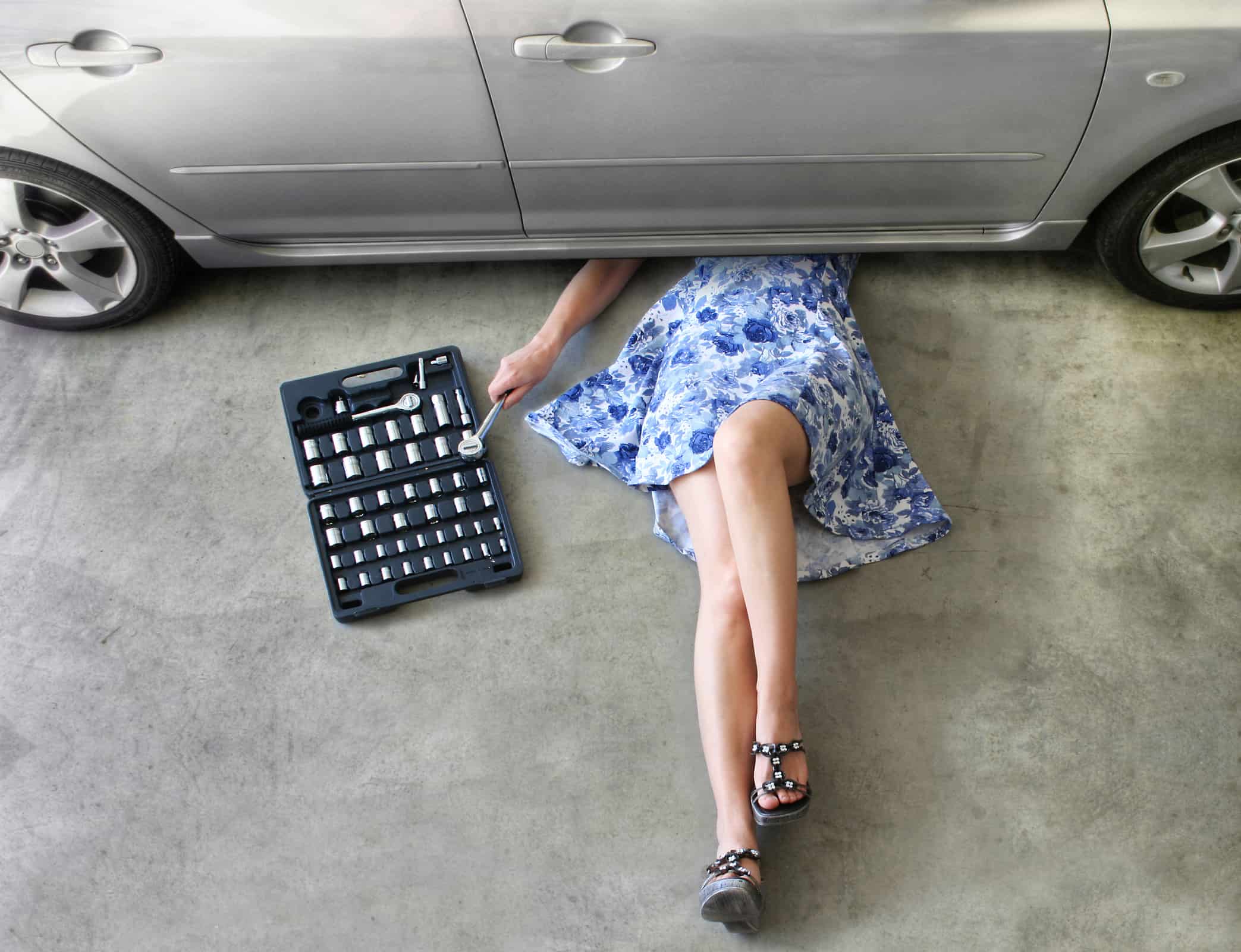 Young woman fixing a car in a garage.